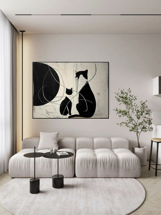 Original black cat art creates a grounded, bold focal point over a plush white modular sofa in a brightly lit contemporary room.