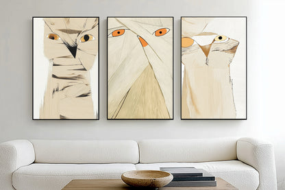 Three abstract cat artworks on a wall above a white sofa.