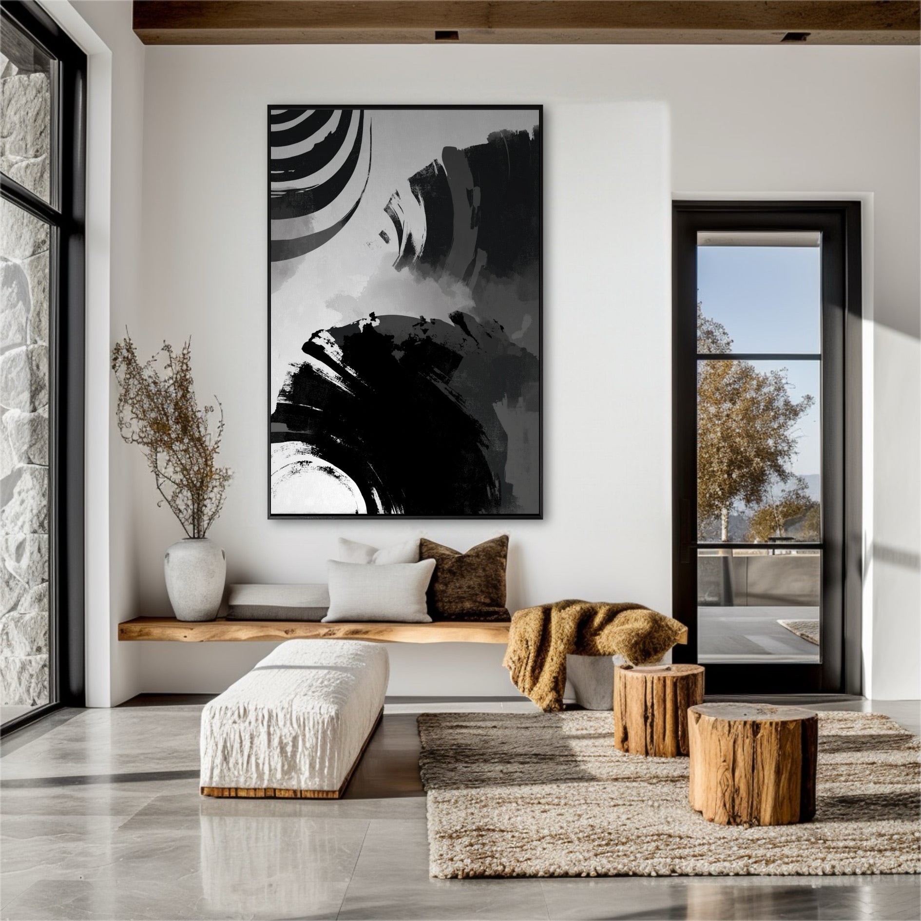 Large black and white gestural art in a rustic modern entryway with a wood bench, stone wall, and tree stump tables.