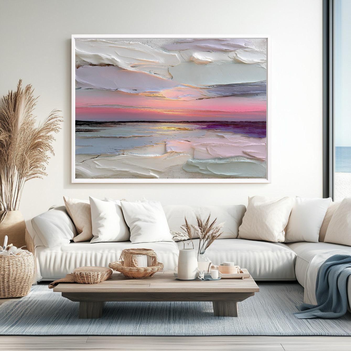 Large textured seascape art echoes the ocean view from the window, harmonizing with the white sofa, blue rug, and light coastal decor.