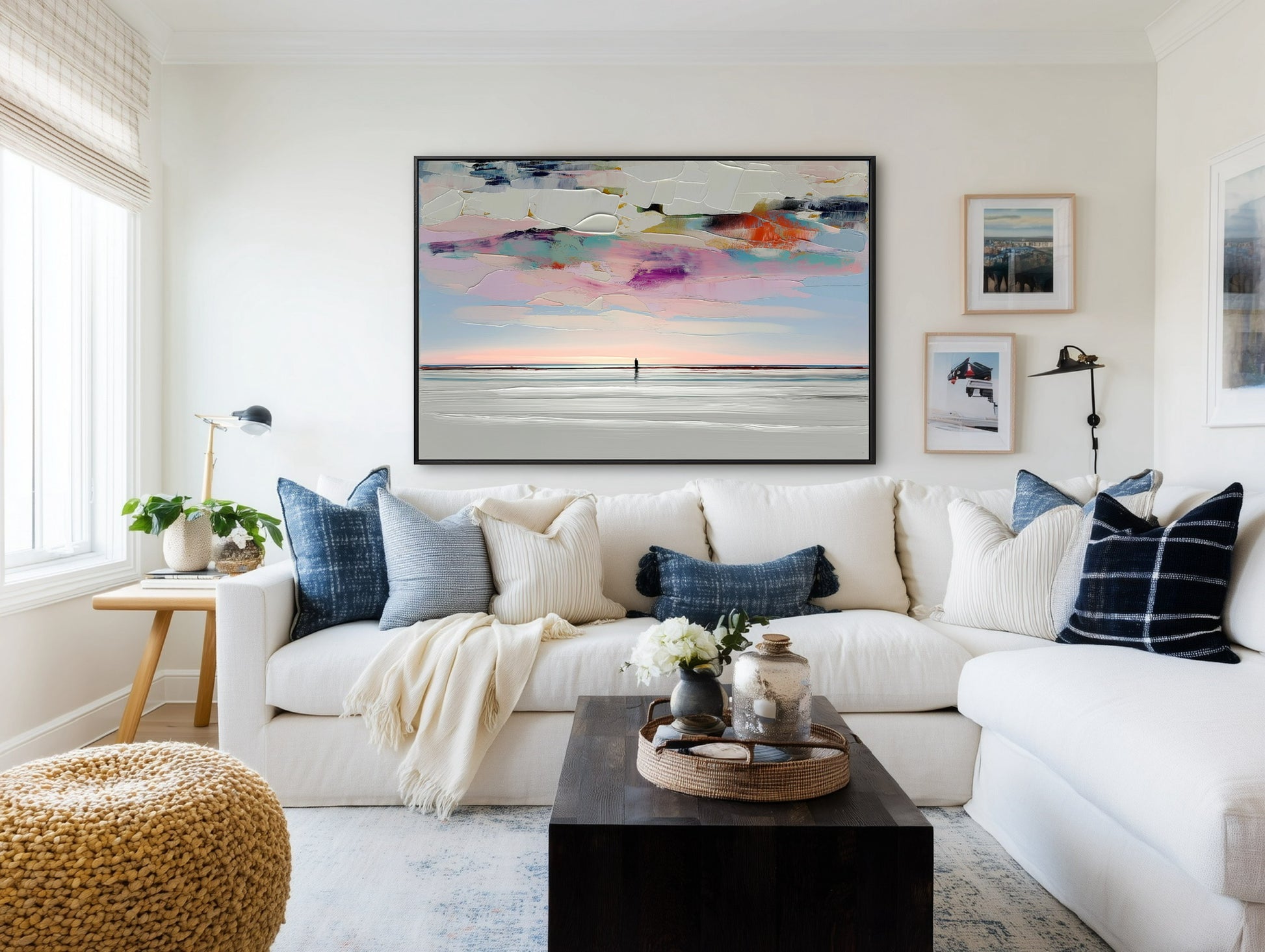 A large abstract landscape painting with a textured sky hangs above a white sectional sofa in a modern farmhouse living room.